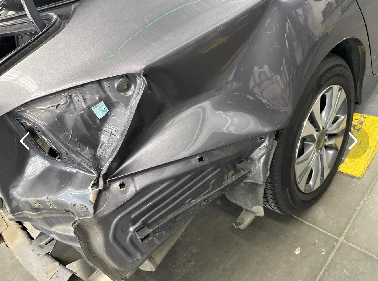 Crushed bumper and fender damage on a gray sedan before bumper repair at JNG